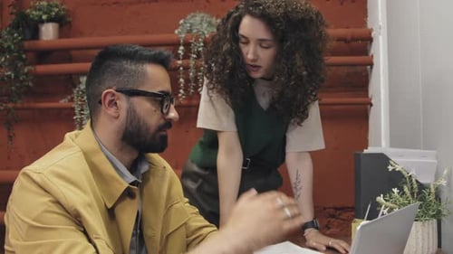 Man and Woman Collaborating at Work on Laptop