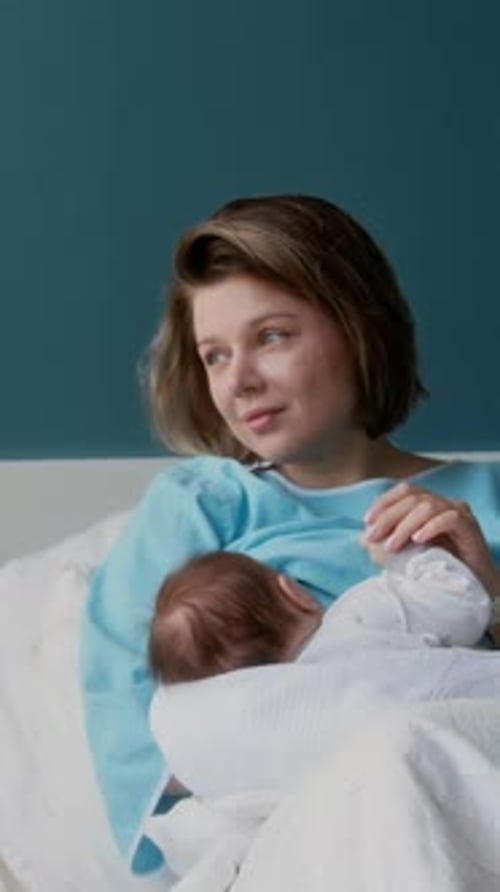 Mother Breastfeeding Newborn Baby in Hospital Bed