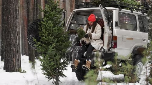 Woman Assembles Small Christmas Trees in Snowy Forest