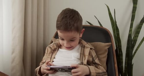 Young Boy Playing on Smartphone in Chair