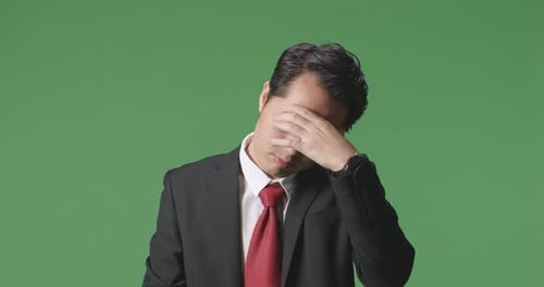 An Asian Business Man Having Headache While Standing In Front Of Green Screen