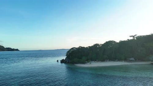 Aerial shot of a stunning island at sunset, with golden hues reflecting off the calm ocean.