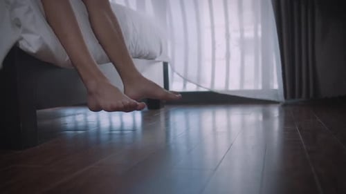 Bare Legs and Feet Dangling off Bed in Bedroom