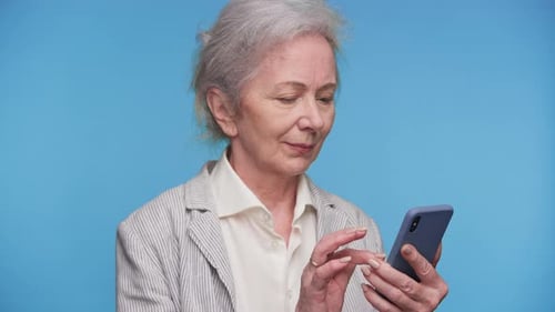 Elderly Woman Scrolling on Smartphone on Blue Background