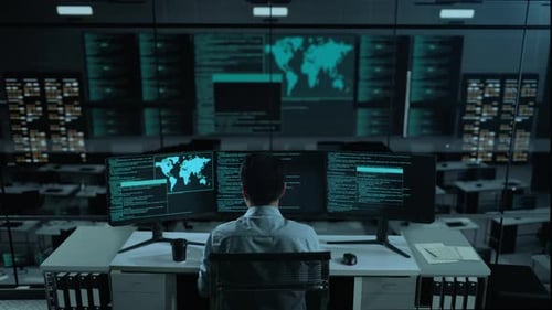Asiatischer Mann benutzt Computer, um Code mit mehreren Bildschirmen im Büro zu schreiben