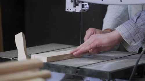 A man works with wood in a workshop. Working with wooden blanks. A man drills holes in wooden blanks