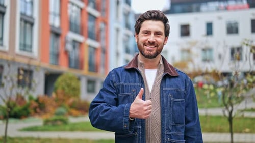 Smiling Man Gives Thumbs Up in Urban Setting