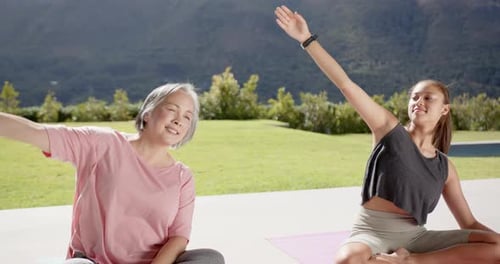 Women practicing yoga in a sunny backyard