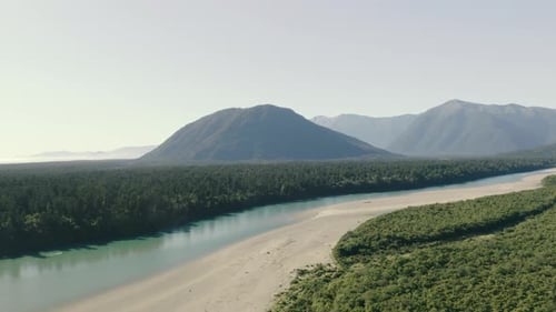 Aerial panning left to right shot of a river with a mountainous range in the background in the west