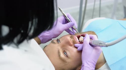 Woman Dentist Doing Treatment for Male Patient Holding Dental Tools Wearing Rubber Gloves Close Up