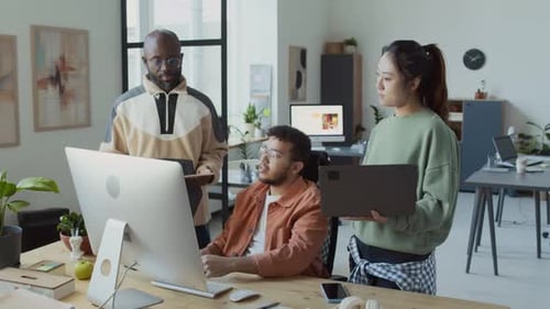 Verschiedene Programmierer stehen am Computer und diskutieren über das Projekt
