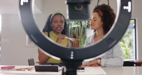 Diversas amigas escogiendo rubor, brochas y enseñando a mezclar bajo una luz anular en la cocina