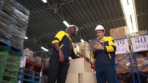 Two warehouse workers are reviewing the list of items based on the documentation