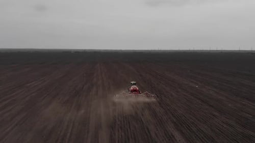Green tractor working on the field planting sunflower