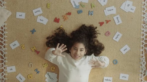 Happy Child Waving Surrounded by Letters and Flashcards