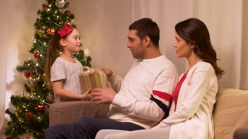 Family at Christmas with Gift by Decorated Tree