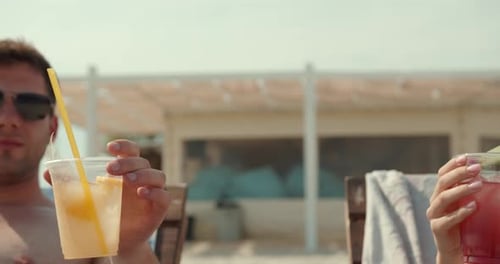 Cheerful Couple with Cocktails Sunbathing on the Beach