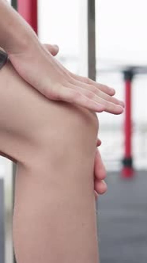 Adult Massaging Sore Knee in Gym Close-up
