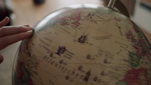 Nahaufnahme einer Hand, die einen Vintage-Globus dreht und in Ostasien landet.
