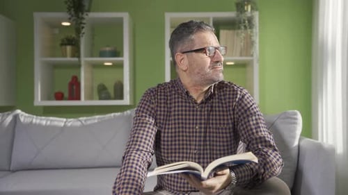 Man Reading Book with Glasses in Living Room