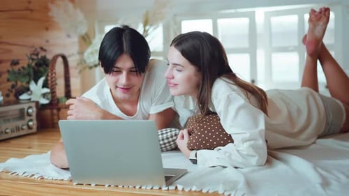Couple Lying On Floor Looking At Laptop