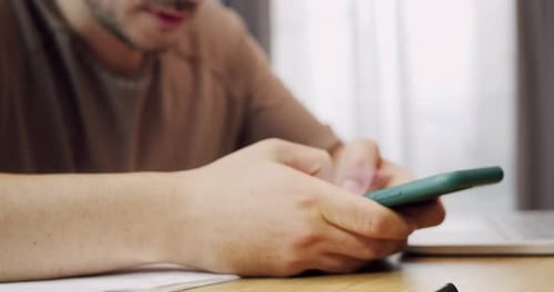 Close Up of Man in Sitting at Desk Holding Smartphone and Chatting at Laptop on Table Indoors Male
