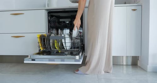 Woman Loading Dishes Into Dishwasher in Modern Kitchen