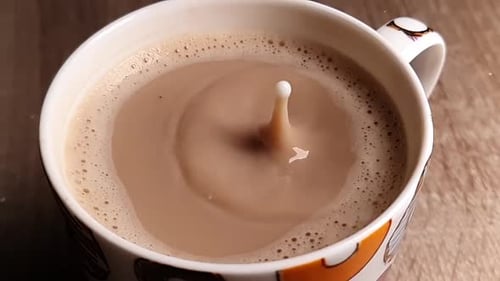 Drop of liquid splashing into coffee cup