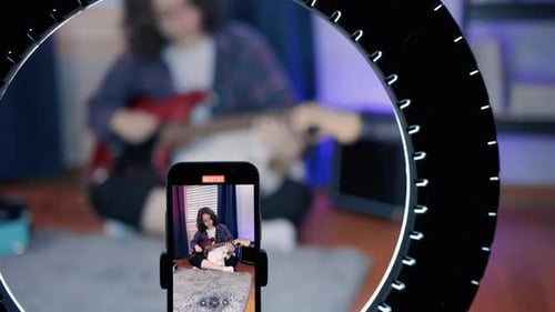 Young Adult Playing Guitar and Filming Video