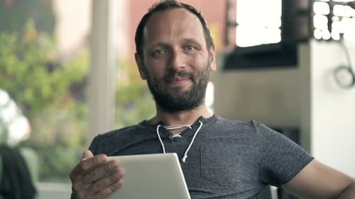 Portrait of Happy, Young Man with Tablet Computer Sitting in Cafe 30s