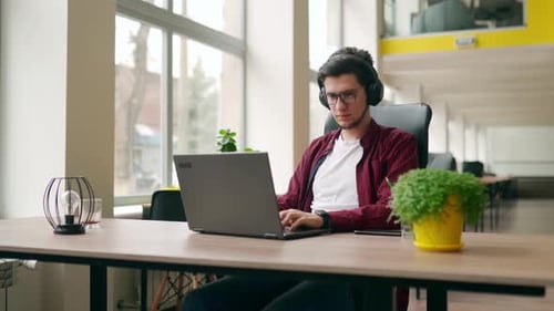 Young Stylish Customer Support Service Worker Removes Headphones Looking at Camera Office Worker