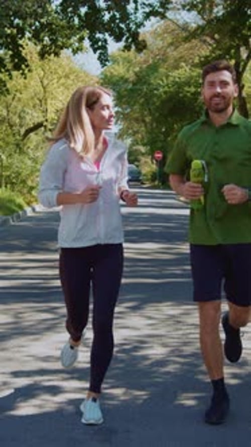 Two Joggers Out Enjoying a Beautiful Morning Run Together in a Scenic Green Park Setting