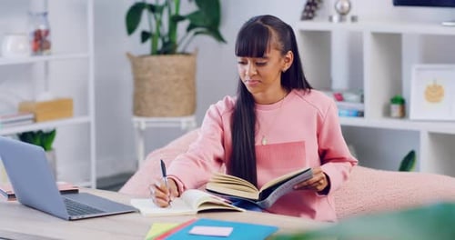 School student doing distance learning with online class and writing notes during a video