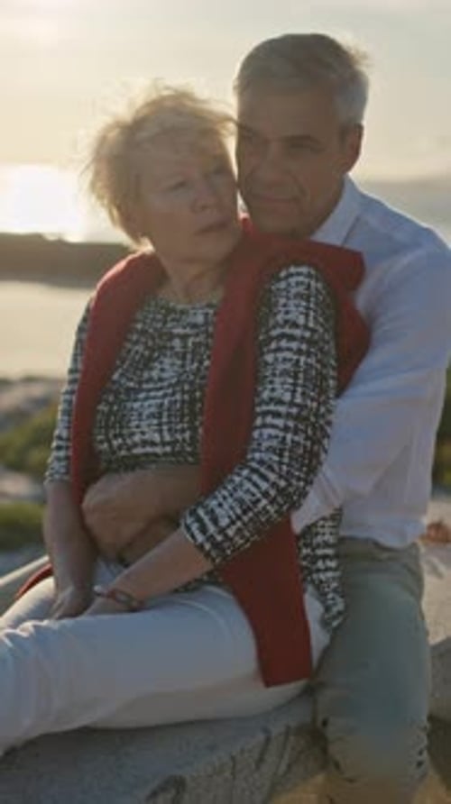 Senior Couple Embracing on Bench at Sunset By the Sea
