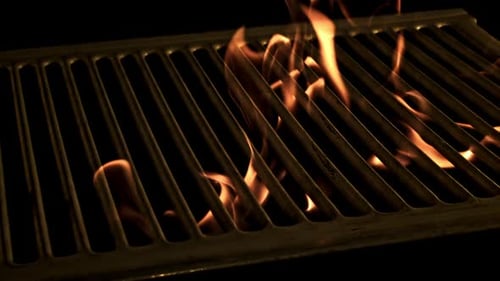Eine helle Feuerflamme brennt durch den Grill