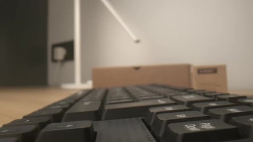Person Types on Computer Keyboard Against Cardboard Boxes