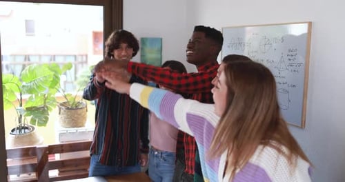 Happy young adults putting hands together in room