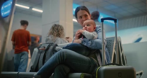 Adult Woman with Two Little Kids Sitting and Waiting for Airplane Flight in Departure Lounge of