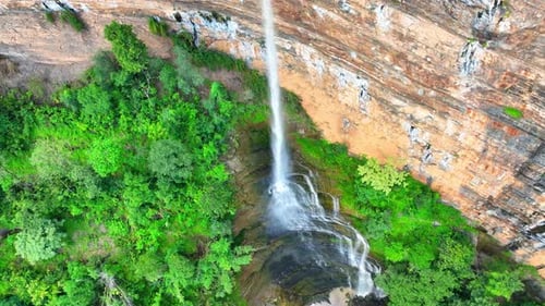 Drone captures majestic waterfall cascading from cliff.