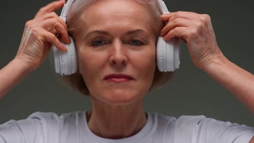 Smiling Woman Puts On Headphones, Listens to Music