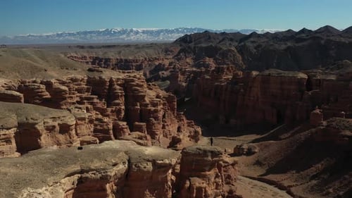 Revealing cinematic drone shot of the Charyn Canyon in Kazakhstan with a person standing on the rock