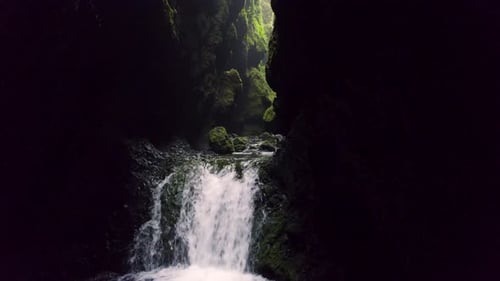 Geheime Dark Fantasy Wasserfallhöhle Grünes Moos. Langsamer Flug aus der Luft rückwärts entlang des Waterfall River
in