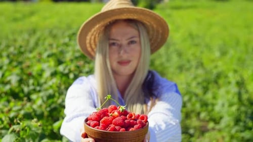 Young Woman Holds Bowl of Fresh Raspberries