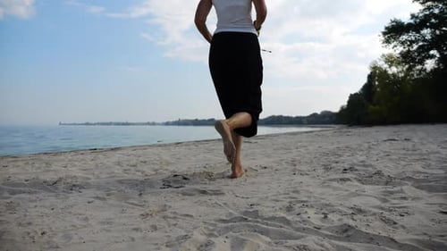 Nackte Füße einer erwachsenen Frau, die am Strand auf Sand joggt, mit Meereslandschaft im Hintergrund, weibliche Beine