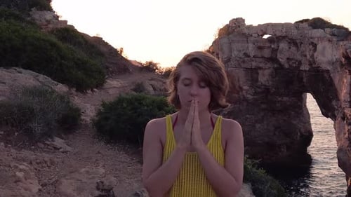 Woman Meditating Peacefully by Rocky Ocean Coastline