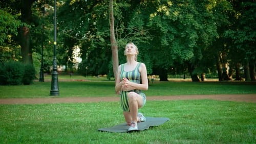 Woman Doing Warm Up Before Workout Stretching Exercise on Fitness Mat in Public Park