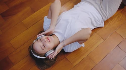 Woman Lies on Floor Listening to Music