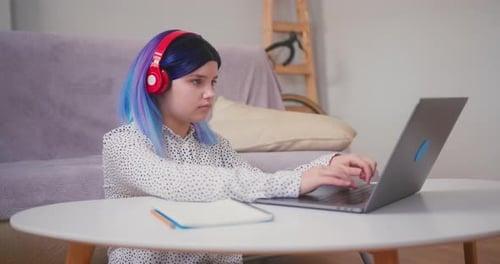 Young Adult Works at Laptop With Headphones On