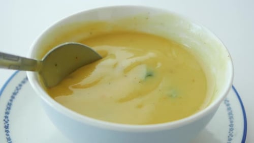 Spoon Stirs a Bowl of Yellow Soup
