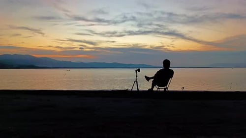 Man Silhouetted Relaxing in Chair at Scenic Sunset